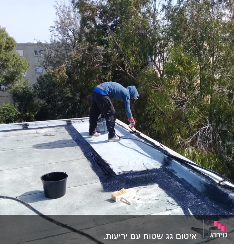 אדם מורח חומר איטום על גג שטוח